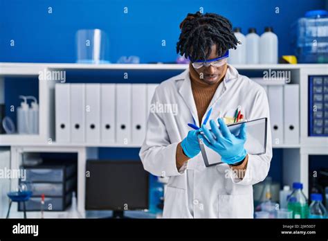 African American Man Scientist Writing On Clipboard At Laboratory Stock