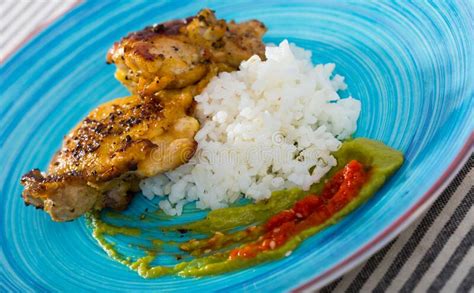 Close Up Of Tasty Rice With Chicken Thighs And Sauces At Plate Stock