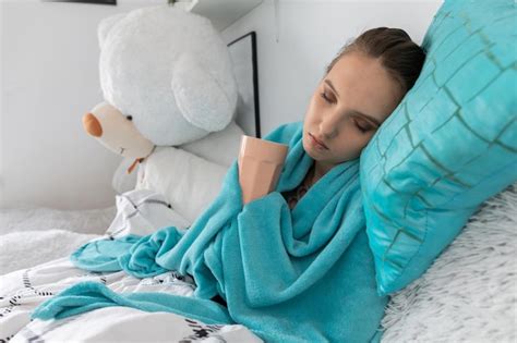 Premium Photo A Young Teenager Drinks Hot Tea With Herbs While Lying On Her Bed Under The Covers