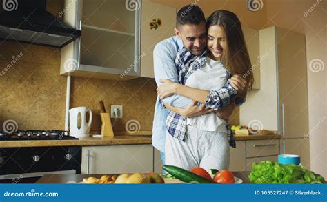 Pares Jovenes Felices Que Abrazan Y Que Hablan En La Cocina Mientras