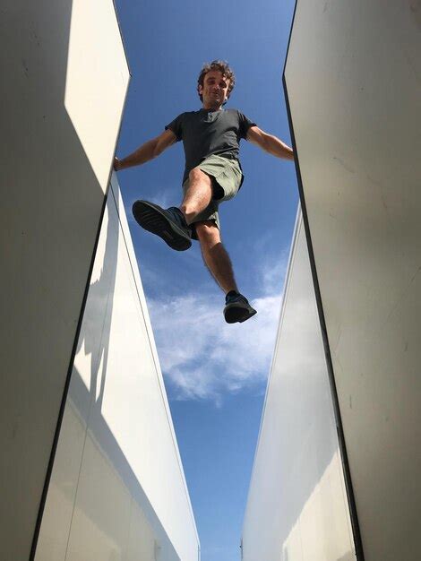 Premium Photo Low Angle View Of Man Jumping Against Sky