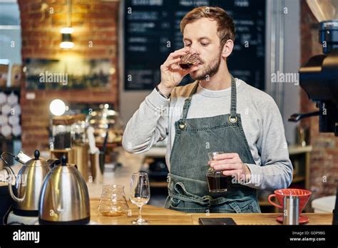 Male Barista Tasting Coffee At Coffee Shop Kitchen Counter Stock Photo