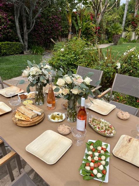 A Table Set With Plates Wine Glasses And Flowers In Vases On Top Of It