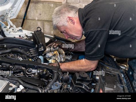 Senior Mechanic Working On Engine Bay Repairing A Oil Leak In Home