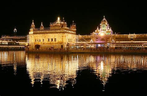 An Illuminated Golden Building In The Middle Of A Lake At Night With