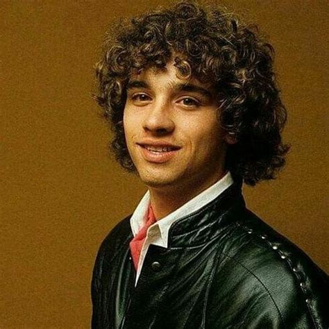 A Man With Curly Hair Wearing A Leather Jacket