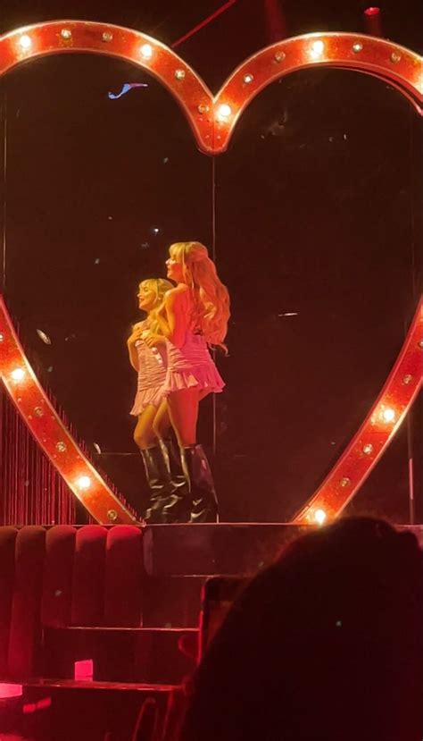 Two Women Standing On Top Of A Stage In Front Of A Heart Shaped Light