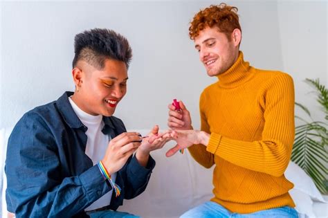 Lindo casal gay se maquiando pintando as unhas e sorrindo sendo romântico dentro de casa em casa