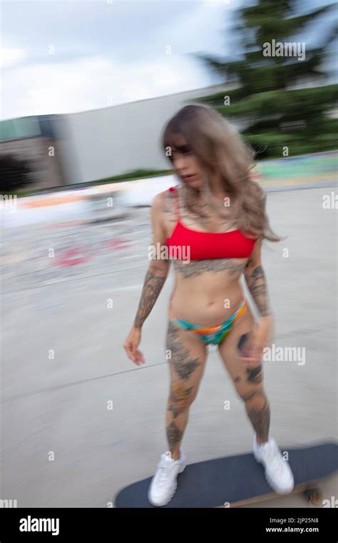 Ein wunderschönes tätowiertes Model mit Skateboard Longboard im Bikini Skateboarding im