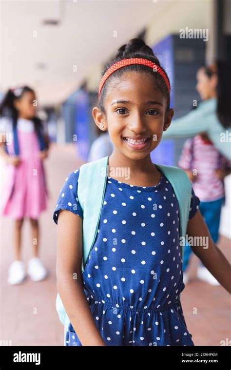 Young biracial girl wearing polka-dot dress and backpack is smiling ...