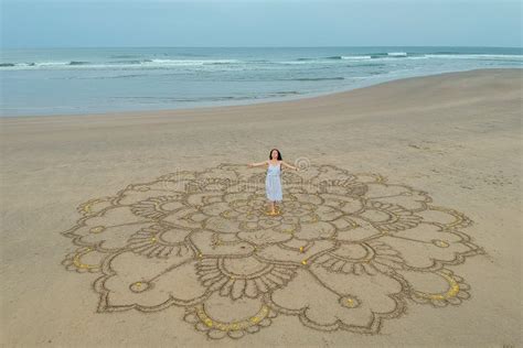 A Large Mandala Painted On The Sand On The Ocean With A Girl In The