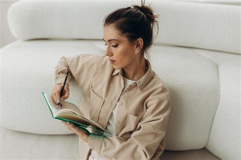 Premium Photo Pretty Brunette Writing Notes While Sitting On The Floor Near Couch At Home In
