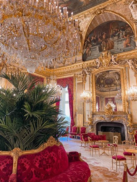 An Ornately Decorated Room With Red Couches And Chandeliers