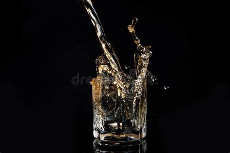 Whiskey Pouring Into Glass With Ice Isolated On Black Background Stock