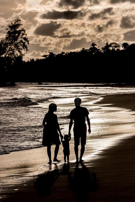 Silueta De La Familia En La Playa En La Puesta Del Sol Imagen De