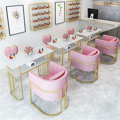 The Interior Of A Nail Salon With Pink Chairs And Gold Frames On The