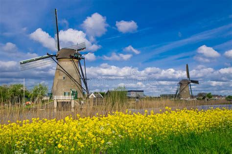 Row Of Traditional Wind Mills Along Blue Canal In Kinderdijk Holland