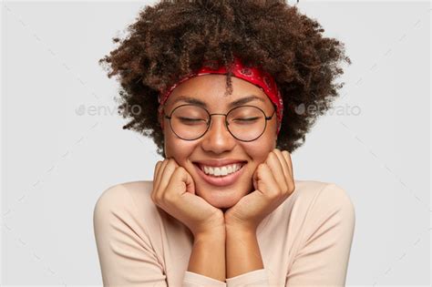 Close Up Shot Of Satisfied Dark Skinned Woman With Shining Smile Keeps