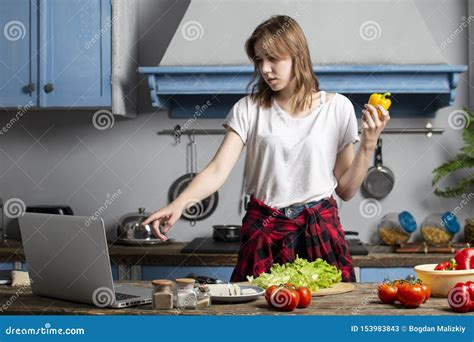 Young Girl Prepares A Vegetarian Salad In The Kitchen And Looks Into A