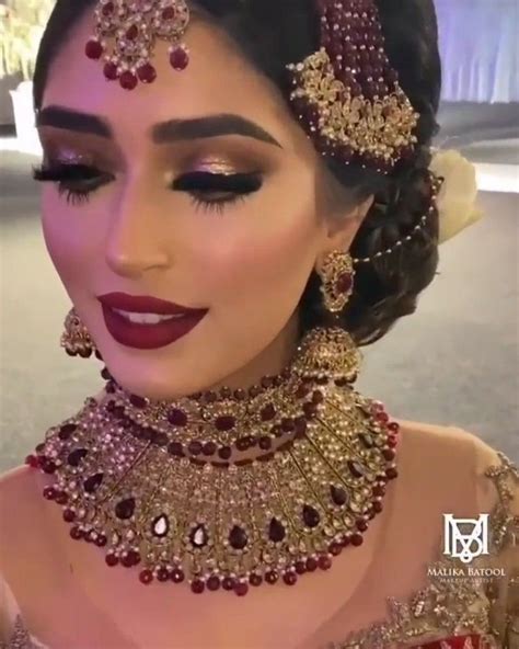 A Woman In A Red And Gold Outfit With Jewelry On Her Head Looking Down