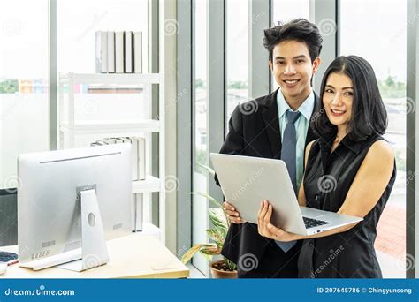 Asian Businessman And Businesswoman Holding A Laptop Computer Were