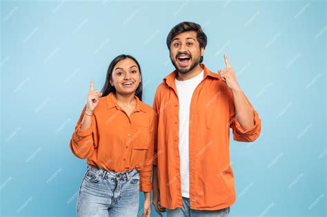 Premium Photo Excited Couple Pointing Upwards Together On Blue Background