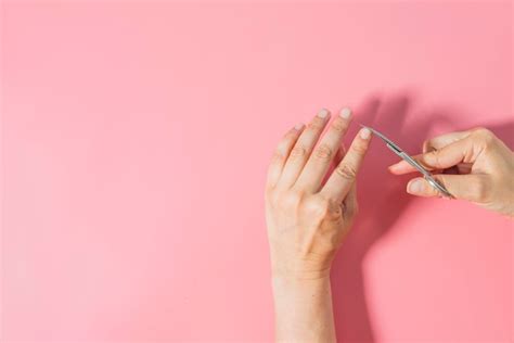 Premium Photo Close Up Of Woman Cutting Nails Against Pink Background