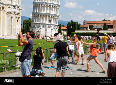 Some Tourists Posing For The Typical Photo In The Leaning Tower Of Pisa