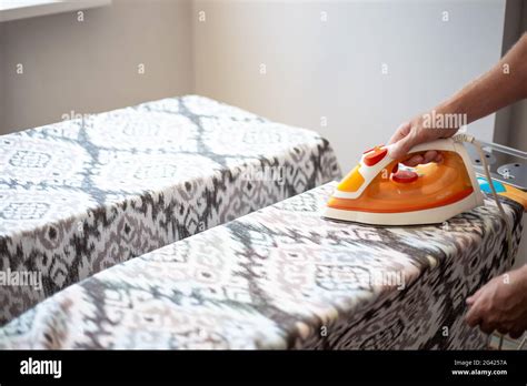 A Man Ironing Linen With An Electric Iron On An Ironing Board Help