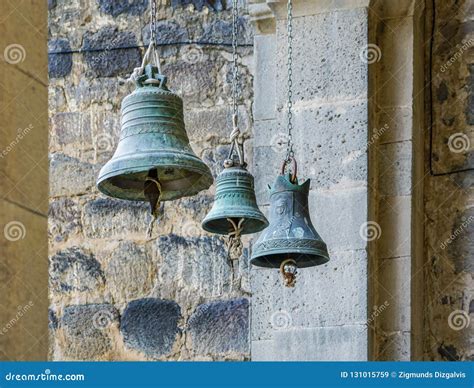 Three Church Bells Of Small Medium And Large Size Hanging In Chains