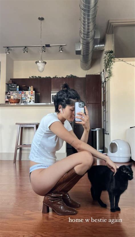 A Woman Kneeling Down Next To A Black Cat And Taking A Selfie With Her