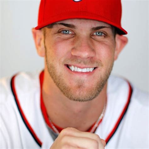 A Man In A Baseball Uniform Holding A Bat And Smiling At The Camera