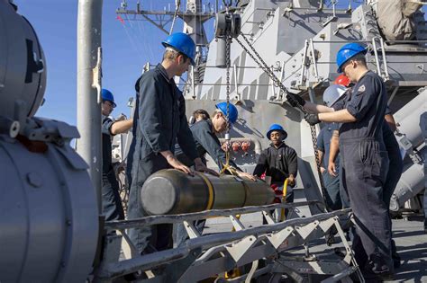 USS Decatur (DDG 73) sailors load a torpedo into a surface vessel