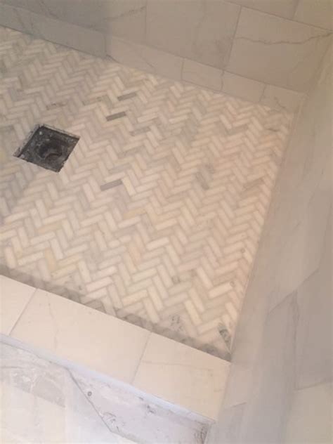 A Bathroom With White Marble Walls And Flooring Including A Shower