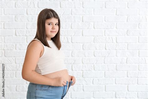 Overweight Girl In Tight Clothes On White Brick Background Stock Photo