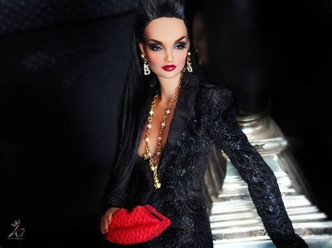 A Barbie Doll Dressed In Black And Holding A Red Purse