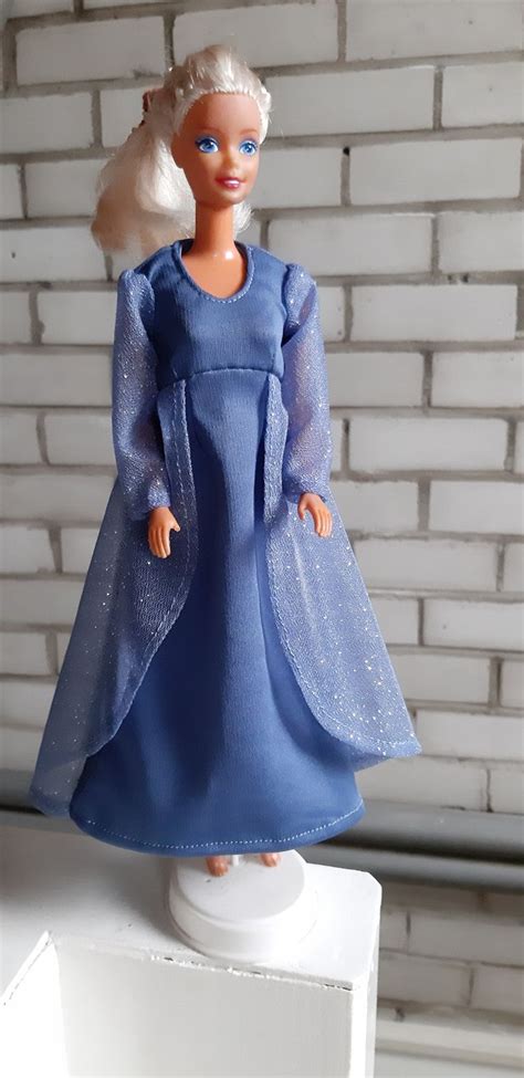 The Doll Is Wearing A Blue Dress And White Hair