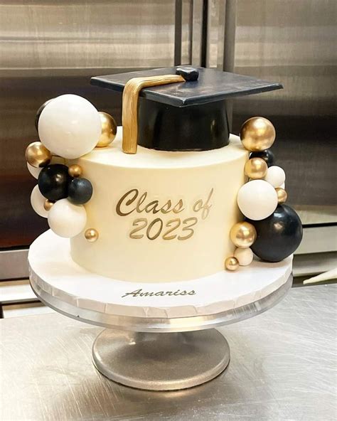 A Graduation Cake Decorated With Black White And Gold Balloons