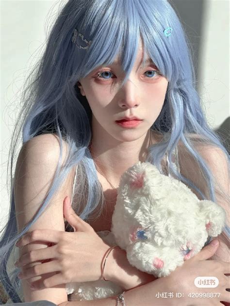 A Woman With Blue Hair Holding A White Teddy Bear