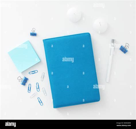 Office Table With Blue Notebook Paper Clips Pen And Post It Notes Top