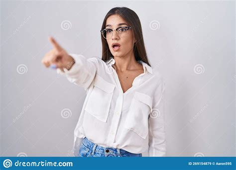 Young Brunette Woman Wearing Glasses Pointing With Finger Surprised Ahead Open Mouth Amazed