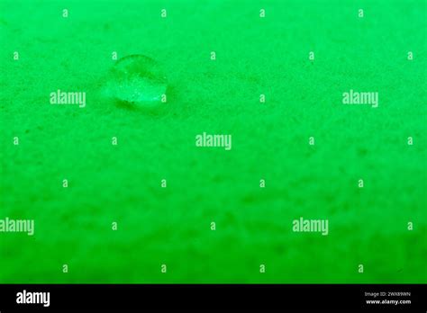 Water Drop On Top Of White Fabric Sheet With Green Light Stock Photo