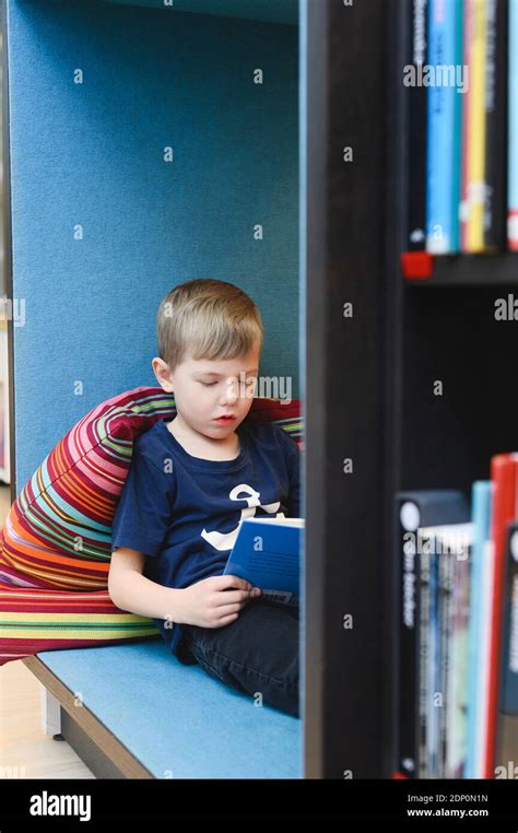 Boy reading book in library Stock Photo - Alamy