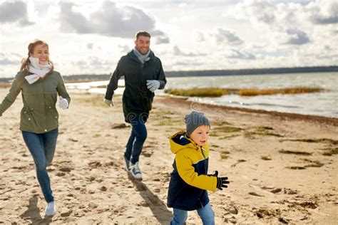 Família Feliz Que Corre Ao Longo Da Praia Do Outono Imagem de Stock