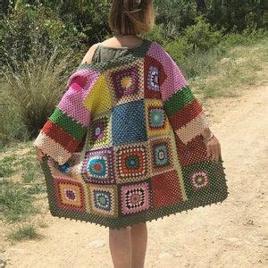 A Woman Walking Down A Dirt Road Wearing A Colorful Crocheted Ponchy