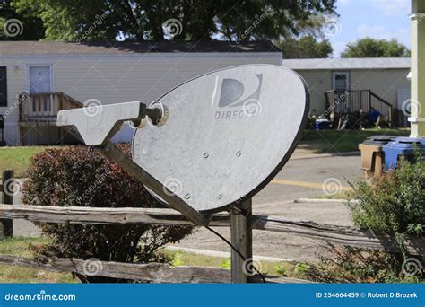 A Directv Satellite Dish In A Yard With A Fence And Green Grass With