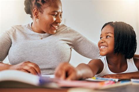 Mère avec une jeune fille apprenant avec des livres à la maison et