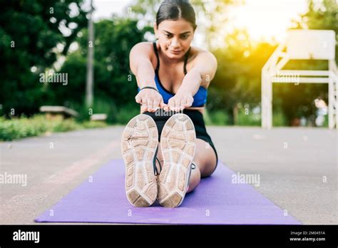 Fille sportive qui s étire les jambes assise sur un tapis dans un parc