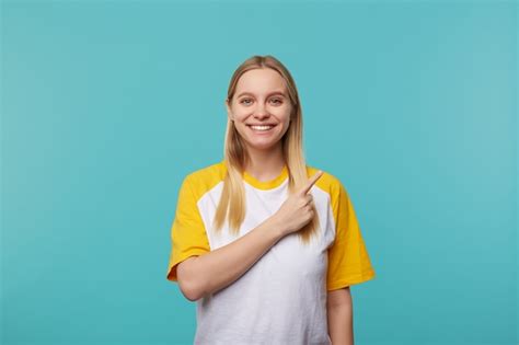 Enthousiaste Jeune Belle Femme Blonde Avec Une Coiffure Décontractée Montrant De Côté Avec L