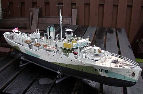 A Model Ship Sitting On Top Of A Wooden Table Next To A Fenced In Area